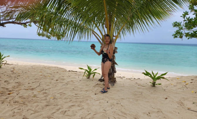 Woman holding coconut on beach